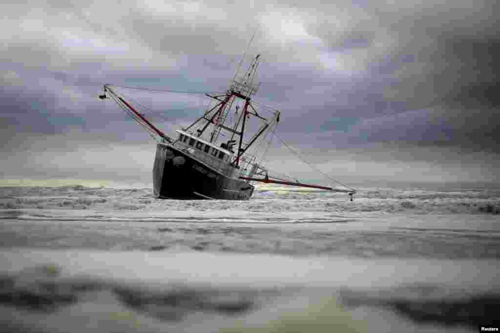 High seas and strong winds stranded the 76-foot commercial fishing vessel Carolina Queen III off New York&#39;s Rockaway Beach and capsized a U.S. Coast Guard boat that rushed to help, but no one was injured, a Coast Guard spokeswoman said.