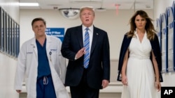 President Donald Trump, center, accompanied by and first lady Melania Trump, right, and Dr. Igor Nichiporenko, left, speak to reporters while visiting with medical staff at Broward Health North in Pompano Beach, Fla., Feb. 16, 2018.