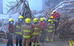 Petugas pemadam kebakaran di lokasi robohnya perancah gedung apartemen saat cuaca buruk di Hong Kong, Jumat, 8 Oktober 2021. (Videograb TVB via AP)