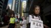 FILE - A pro-democracy protester, wearing a mask depicting a Chinese political prisoner, carries a placard, with the prisoner's name and his charges, during a protest calling for the release of political prisoners in Hong Kong, Oct. 1, 2013. 