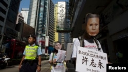 A pro-democracy protester, wearing a mask depicting a Chinese political prisoner, carries a placard, with the prisoner's name and his charges, during a protest calling for the release of political prisoners in Hong Kong, Oct. 1, 2013. 