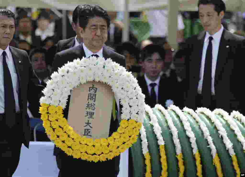 Perdana Menteri Jepang Shinzo Abe memegang karangan bunga dalam upacara peringatan 70 tahun pemboman Nagasaki di Nagasaki, Jepang selatan (9/5).&nbsp;​(AP/Eugene Hoshiko)