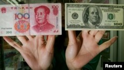香港一家貨幣兌換店裡的僱員展示人民幣和美元百元鈔票