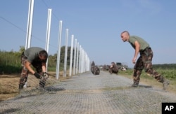 Hungarian soldiers work on a fence that is being built at the border with Croatia, near the village of Beremend, Hungary, Sept. 22, 2015.