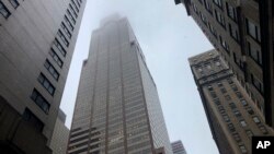 La lluvia y el humo cubren el tope del edificio cerca de la calle 51 y la Séptima Avenida en Nueva York, el lunes 10 de junio de 2019, donde un helicóptero se incendió cuando trató de aterrizar en el techo del rascacielos.