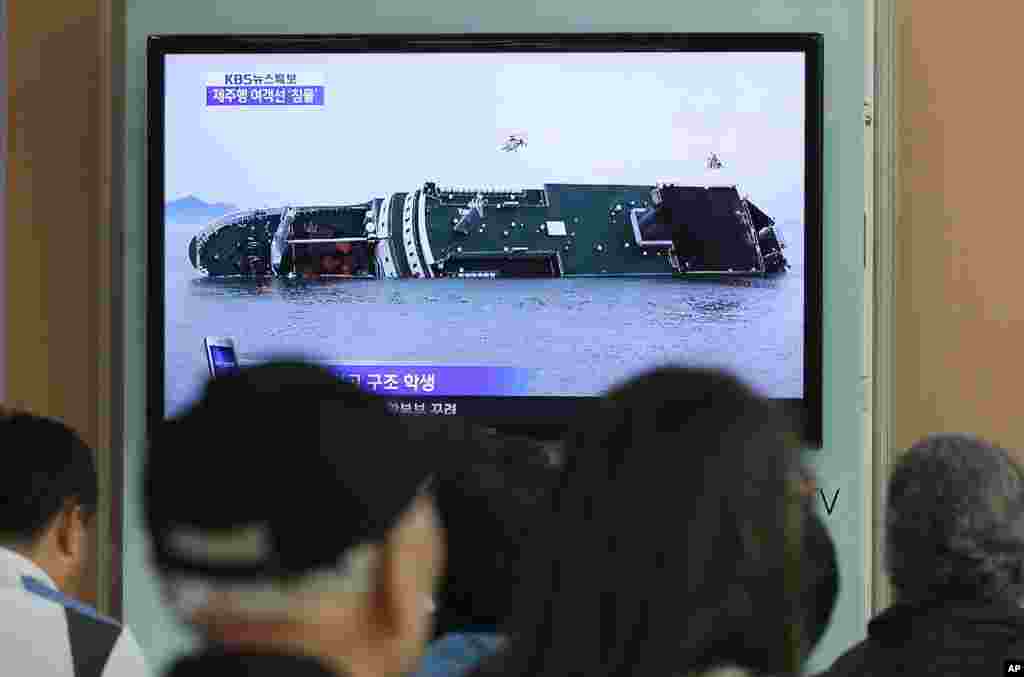 People watch a TV news program showing a sinking passenger ship, at Seoul Railway Station in Seoul, April 16, 2014.