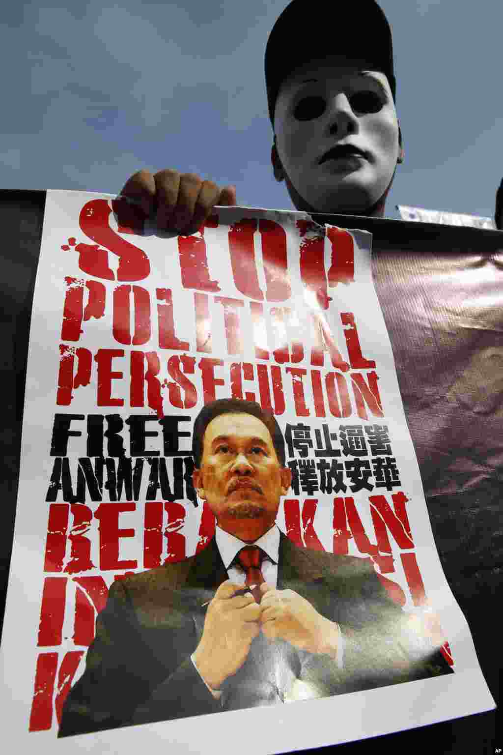 A supporter holds a poster of Malaysian opposition leader Anwar Ibrahim during his final hearing of his sodomy conviction in Putrajaya, Malaysia, Tuesday, Oct. 28, 2014. Anwar was found guilty by the Malaysian Court of Appeal on March 7, 2014 of having so