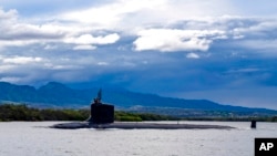 FILE - In this photo provided by U.S. Navy, a submarine departs Joint Base Pearl Harbor-Hickam, Sept. 1, 2021. 