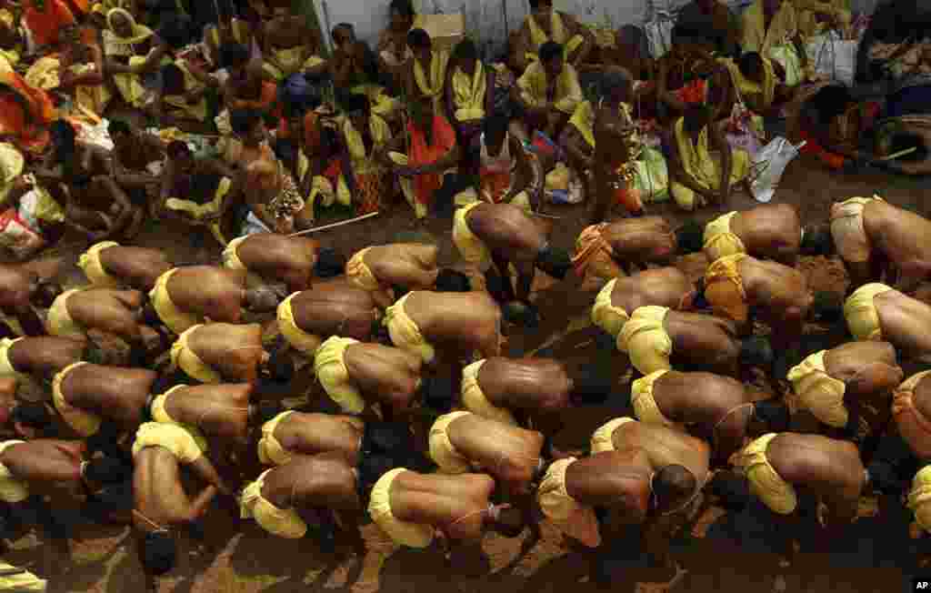 Sambil memegang kaki mereka para laki-laki India ini berjalan di pasir panas sebagai bagian dari ritual festival tahunan Danda atau upacara menghukum diri sendiri di desa Harigada di distrik Ganjam, negara bagian&nbsp; Orissa, India, 3 April 2014. &nbsp;