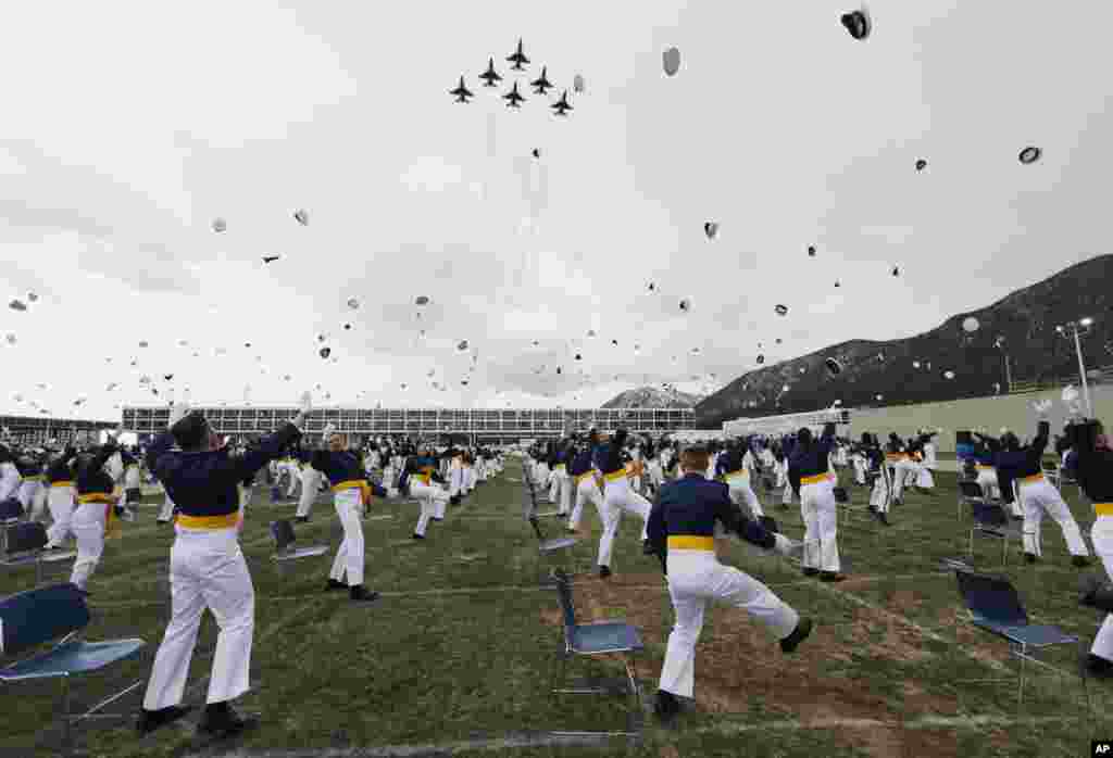 Los cadetes lanzan sus gorras al aire después de ser promovidos a oficiales mientras los aviones Thunderbirds vuelan sobre la ceremonia de graduación.
