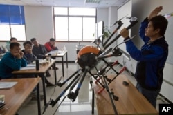 FILE - An instructor explains the operation of a drone to students at a school run by TT Aviation Technology in Beijing, Oct. 17, 2015. China has quickly emerged as a leading player in the international race for drone manufacturing.