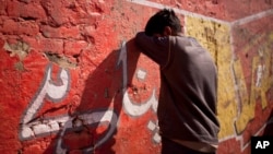 A drug addict leans on a wall after injecting himself with a dose of heroin on a street in Rawalpindi, Pakistan, Feb. 14, 2012.