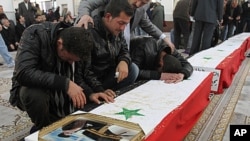 Syrian men mourn over the coffin of one of 11 Syrian police officers who were killed in an explosion in the Midan neighborhood, during a mass funeral procession at Al-Hassan mosque, in Damascus, January 7, 2011.