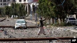 A Houthi rebel fighter walks on a street littered by debris following a Saudi-led airstrike in Yemen's capital, Sana'a, April 20, 2015.