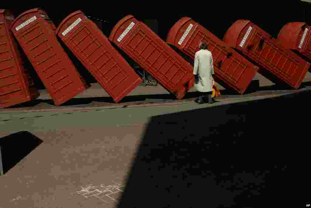 A woman looks at &quot;Out of Order&quot; &mdash; a 1989 red phone box sculpture by British artist David Mach, in Kingston upon Thames, London.