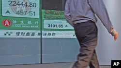 A man walks past a panel displaying the Hang Seng index trend at the end of the trading day at the Hong Kong Stock Exchange, July 22, 2011