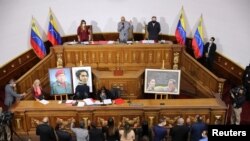 Los nuevos miembros de la Asamblea Nacional de Venezuela levantan la mano durante una sesión en Caracas, Venezuela, el 7 de enero de 2021.