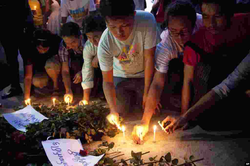 Warga menyalakan lilin di depan Kedutaan Besar Perancis di Yangon, Myanmar (15/11), untuk menghormati para korban serangan maut di Paris (15/11). ​(AP/Khin Maung Win)