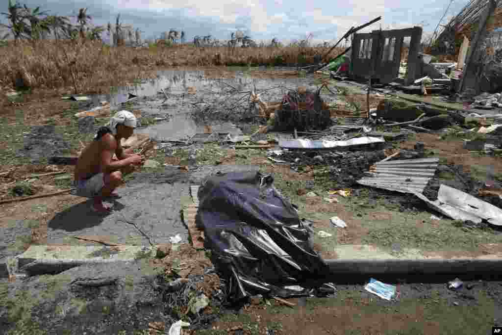 A typhoon survivor sits beside the body bag containing his child in Tacloban, central Philippines, Nov. 20, 2013.