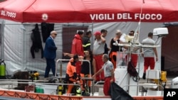 Bomberos y buzos italianos atracan en el puerto de Porticello, en el sur de Italia, el martes 20 de agosto de 2024, mientras los equipos de rescate regresan al lugar donde se hundió un yate para buscar a seis personas, entre ellas el magnate informático británico Mike Lynch.