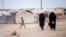 FILE - Women walk in the al-Hol camp that houses refugees, including foreign nationals, in Syria, May 1, 2021. On Jan. 20, 2023, a judge ordered the Canadian government to help bring home four Canadian men being held in Syrian camps.
