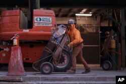 Construction workers handle equipment on Tuesday, Jan. 17, 2023, in New York. (AP Photo/Andres Kudacki)