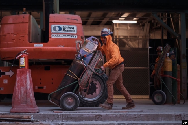 Construction workers handle equipment on Tuesday, Jan. 17, 2023, in New York. (AP Photo/Andres Kudacki)