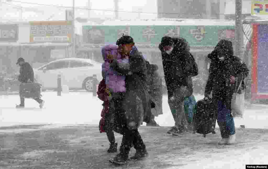 Passengers make their way through a heavy snowstorm to a railway station in Gwangju, South Korea.