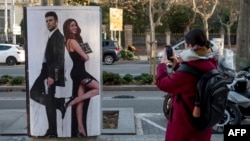 Seorang pejalan kaki memotret mural bergambar mantan bek Spanyol Barcelona Gerard Pique dan penyanyi Kolombia Shakira hasil karya seniman jalanan Italia Salvatore Benintende alias TvBoy di Barcelona, 13 Januari 2023. (Josep LAGO / AFP) 