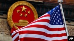 Bendera Amerika Serikat berkibar di sebelah lambang nasional China saat upacara penyambutan di Aula Besar Rakyat di Beijing, 9 November 2017. (Foto: AP)