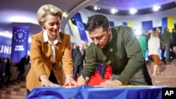 Ukrainian President Volodymyr Zelenskyy and European Commission President Ursula von der Leyen write their wishes on a Ukrainian flag during the EU-Ukraine summit in Kyiv, Ukraine, Feb. 2, 2023.