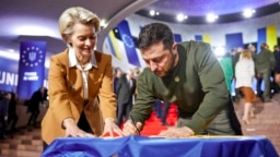 Ukrainian President Volodymyr Zelenskyy and European Commission President Ursula von der Leyen write their wishes on a Ukrainian flag during the EU-Ukraine summit in Kyiv, Ukraine, Feb. 2, 2023.