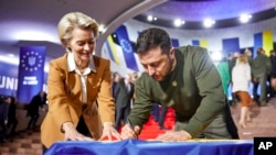 El presidente de Ucrania, Volodymyr Zelenskyy, y la presidenta de la Comisión Europea, Ursula von der Leyen, escriben sus deseos en una bandera ucraniana durante la cumbre UE-Ucrania en Kiev, Ucrania, el 2 de febrero de 2023.