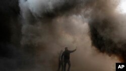 Protesters take pictures of burning tires they set on fire, in front the Central Bank building, during a rally against the Lebanese Central Bank Governor Riad Salameh and the deepening financial crisis in Beirut.