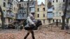 A local resident carries her baby outside of their residential building partially destroyed after a missile strike in Kharkiv, Ukraine, Jan. 30, 2023