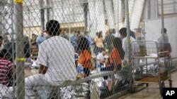FILE - In this photo provided by US Customs and Border Protection, people who've been taken into custody related to cases of illegal entry into the United States sit in one of the cages at a facility in McAllen, Texas, on June 17, 2018. 