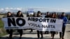 Aktivis lingkungan Albania memegang spanduk saat menggelar aksi protes terhadap rencana pembangunan bandara baru di kawasan Vjose-Narte di Vlora, Albania, 28 Januari 2023. (REUTERS/Florion Goga)