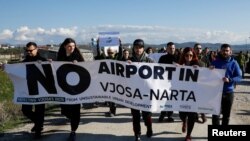 Aktivis lingkungan Albania memegang spanduk saat menggelar aksi protes terhadap rencana pembangunan bandara baru di kawasan Vjose-Narte di Vlora, Albania, 28 Januari 2023. (REUTERS/Florion Goga)