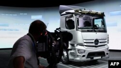 FILE: A cameraman films an electric e-Actros truck at the annual shareholders' meeting of the Daimler Truck Holding AG, in Stuttgart, southern Germany, on June 22, 2022.