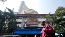 People walk past an electronic signage displaying news on federal budget at the Bombay Stock Exchange (BSE) building in Mumbai, India, Feb. 1, 2023