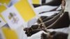 FILE- An attendee holds a Vatican flag and rosary beads ahead of Pope Francis' meeting with bishops, priests, deacons, consecrated persons and seminarians at the Cathedral of Saint Therese in Juba, South Sudan, on February 4, 2023