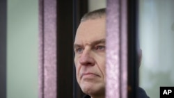 FILE - Journalist Andrzej Poczobut stands in a defendants' cage during a court session in Grodno, Belarus, Jan. 16, 2023. 