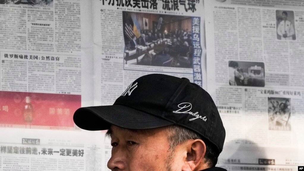 2023年2月6日，北京一男子阅读报刊有关中国间谍气球被美军击落的新闻报道后离开报亭。(photo:VOA)