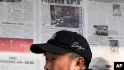 2023年2月6日，北京一男子阅读报刊有关中国间谍气球被美军击落的新闻报道后离开报亭。