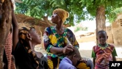 FILE: A displaced woman braids her daughter's hair in Segou, on September 30, 2019. - In central Mali, in the heart of Sahel bogged down in a conflict that worsen since 2012, education has become a luxury.