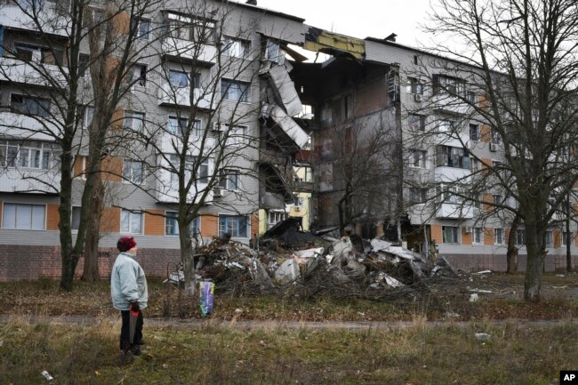 A woman passes by an apartment building damaged following by Russian shelling in Bakhmut, the site of the heaviest battles with the Russian troops, in the Donetsk region, Ukraine, Sunday, Dec. 11, 2022. (AP Photo/Andriy Andriyenko, File)