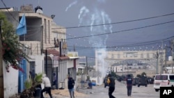 Palestinians run from tear gas fired by Israeli forces raiding Aqbat Jabr camp, southwest of the city of Jericho on Feb. 4, 2023, during a search for the Palestinian suspects behind a shooting attack in a nearby settlement last week.