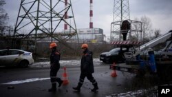 FILE - Utility workers walk next to a power plant after a missile attack in Kyiv, Ukraine, Jan. 26, 2023.