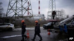 ARCHIVO - Trabajadores de servicios públicos caminan junto a una planta de energía después de un ataque con misiles en Kiev, Ucrania, el 26 de enero de 2023.