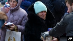 People receive bread and milk and humanitarian aid at a distribution spot in Zaporizhzhya, Ukraine, Feb. 6, 2023.